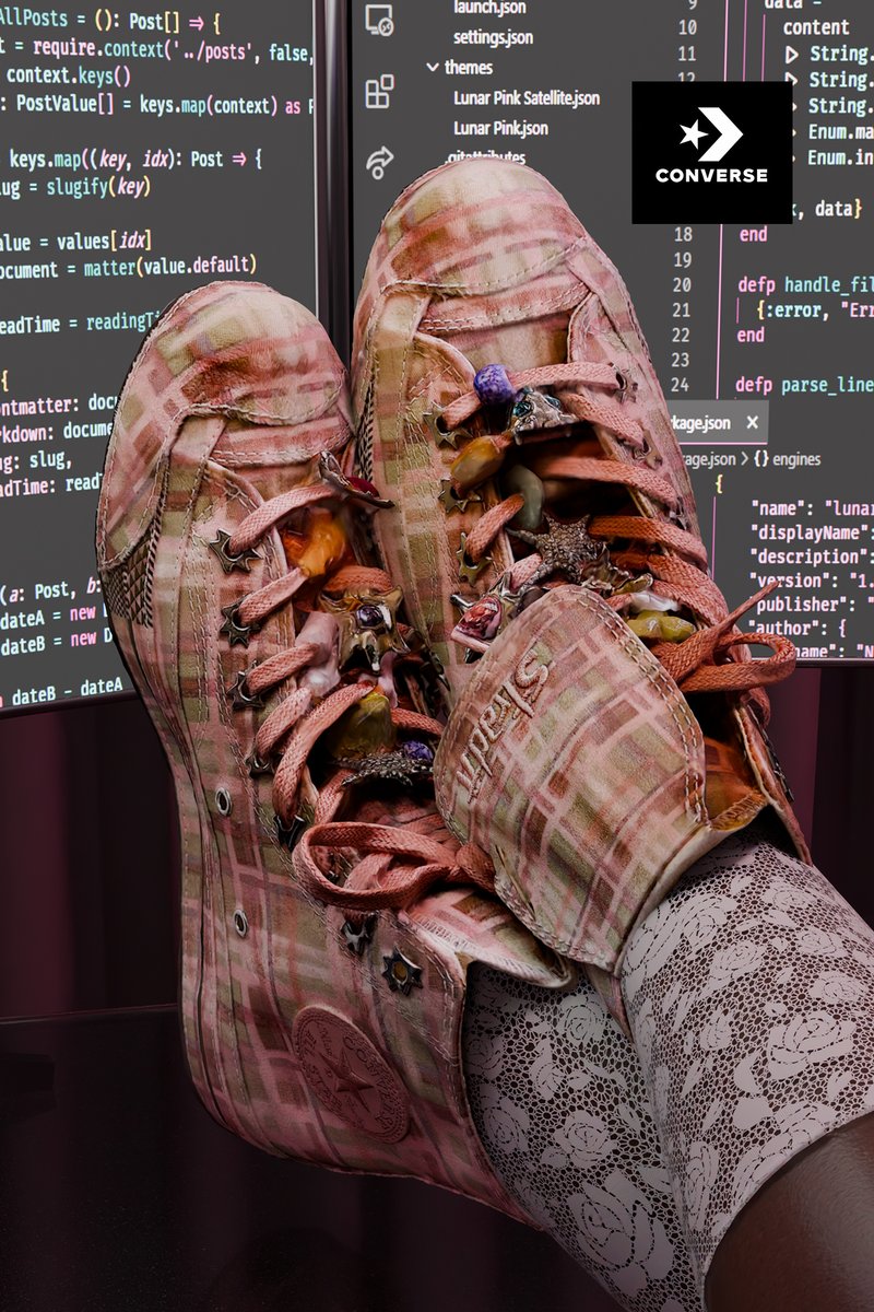 Zapatillas Converse de cuadros rosas con colgantes decorativos en los cordones, usadas sobre medias con patrón de encaje, frente a pantallas de ordenador que muestran código de programación.