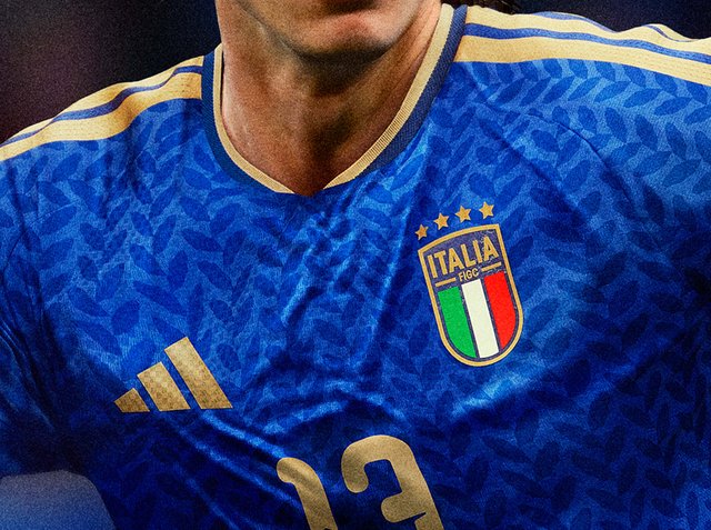 Nahaufnahme eines blauen Italien-Fußballtrikots mit goldenem Adidas-Logo, vier Sternen und der Nummer 13 auf der Brust.
