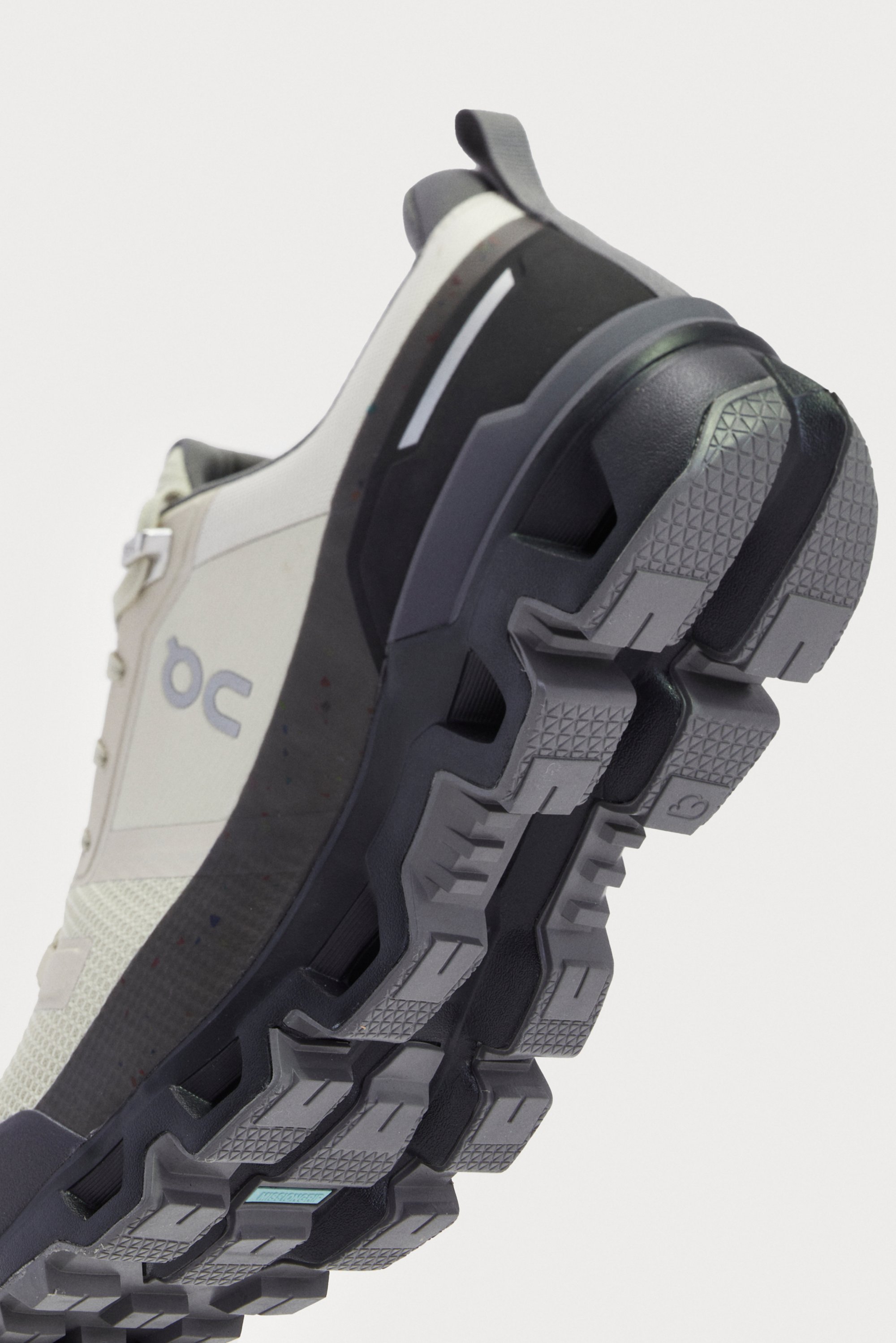 A athletic shoe featuring a white and gray design with a textured black sole, showcasing its modern structure and detailing.