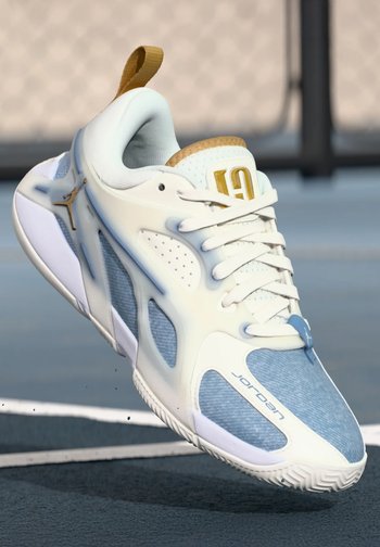 Białe i jasnoniebieskie buty sportowe z teksturowaną cholewką, złotymi akcentami, wyraźnym logo oraz gumową podeszwą z wzorzystym bieżnikiem.