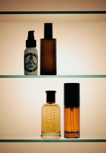 Deux étagères avec quatre flacons cosmétiques : l'étagère du haut contient de l'huile à barbe et une bouteille foncée, l'étagère du bas a du parfum Hugo Boss et de l'huile de beauté Rituals.