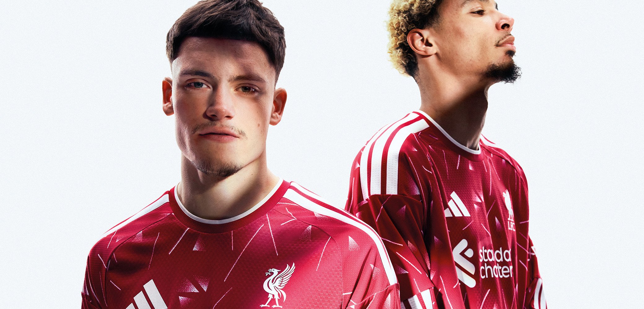 Zwei Männer tragen rote Liverpool-Fußballtrikots mit weißen Streifen und stehen nebeneinander vor einem weißen Hintergrund.