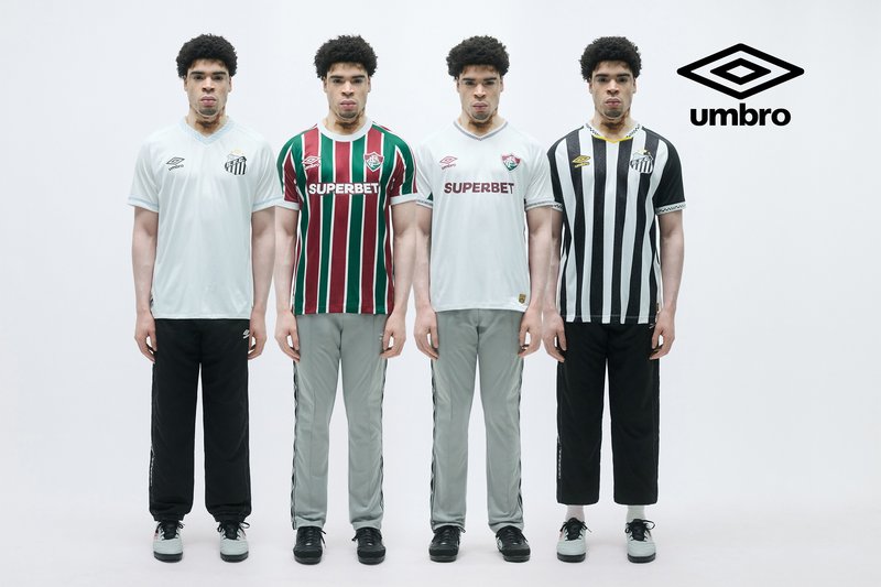 Vier Fußballtrikots, die an Modellen präsentiert werden: weiß, rot-grün gestreift, weiß mit Logo und schwarz-weiß gestreift. Alle kombiniert mit passenden Hosen.