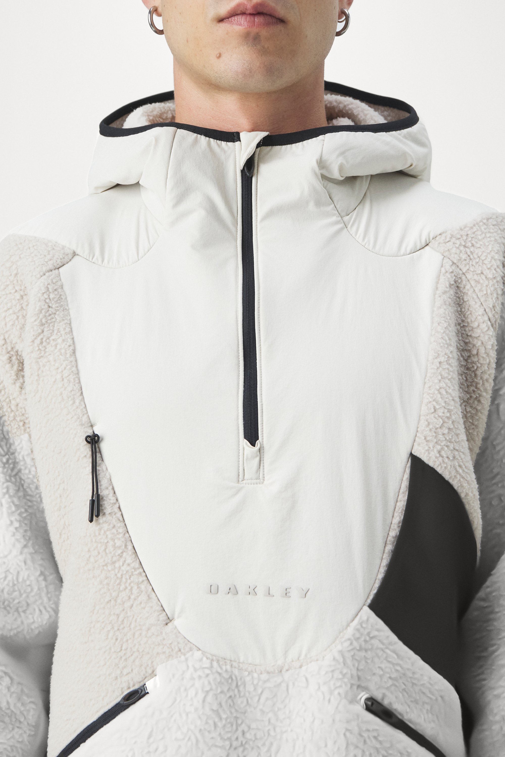 A close-up of a person wearing a stylish, two-tone fleece jacket with a high collar and zip, featuring the Oakley logo on the front.