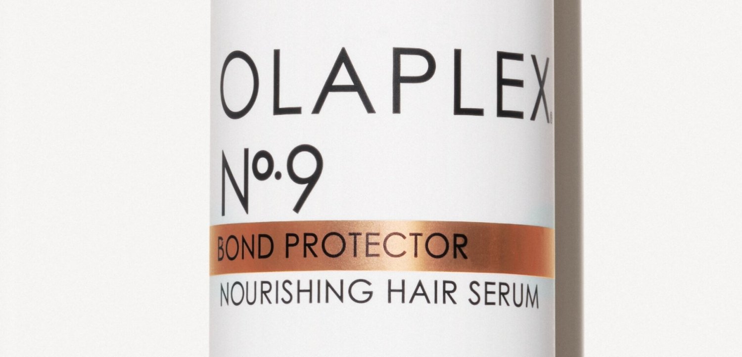 Witte fles met label Olaplex No 9 Bond Protector Nourishing Hair Serum met koperen band die het producttype benadrukt.