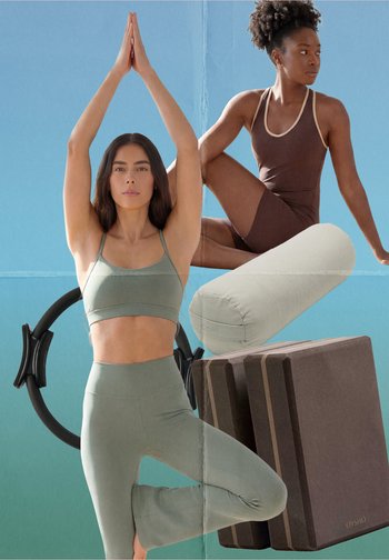 Dos mujeres vestidas con ropa deportiva realizando posturas de yoga con anillo de Pilates, soporte y bloques de espuma sobre un fondo azul verdoso.