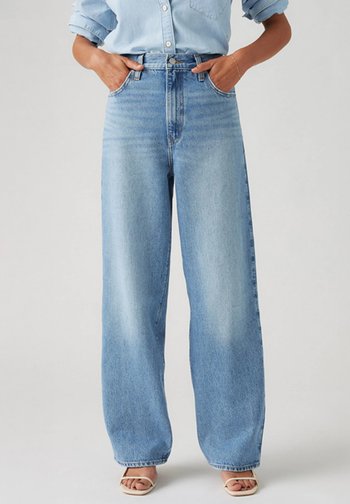 Bredde ben denim jeans i lyseblå med høy midje, knappelukking og frontlommer. Myk tekstur og subtile falming detaljer.
