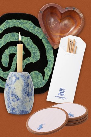 Blue and white marbled candle holder, cream candle, green spiral rug, heart-shaped wooden dish, white envelope with sticks, and pink coasters.