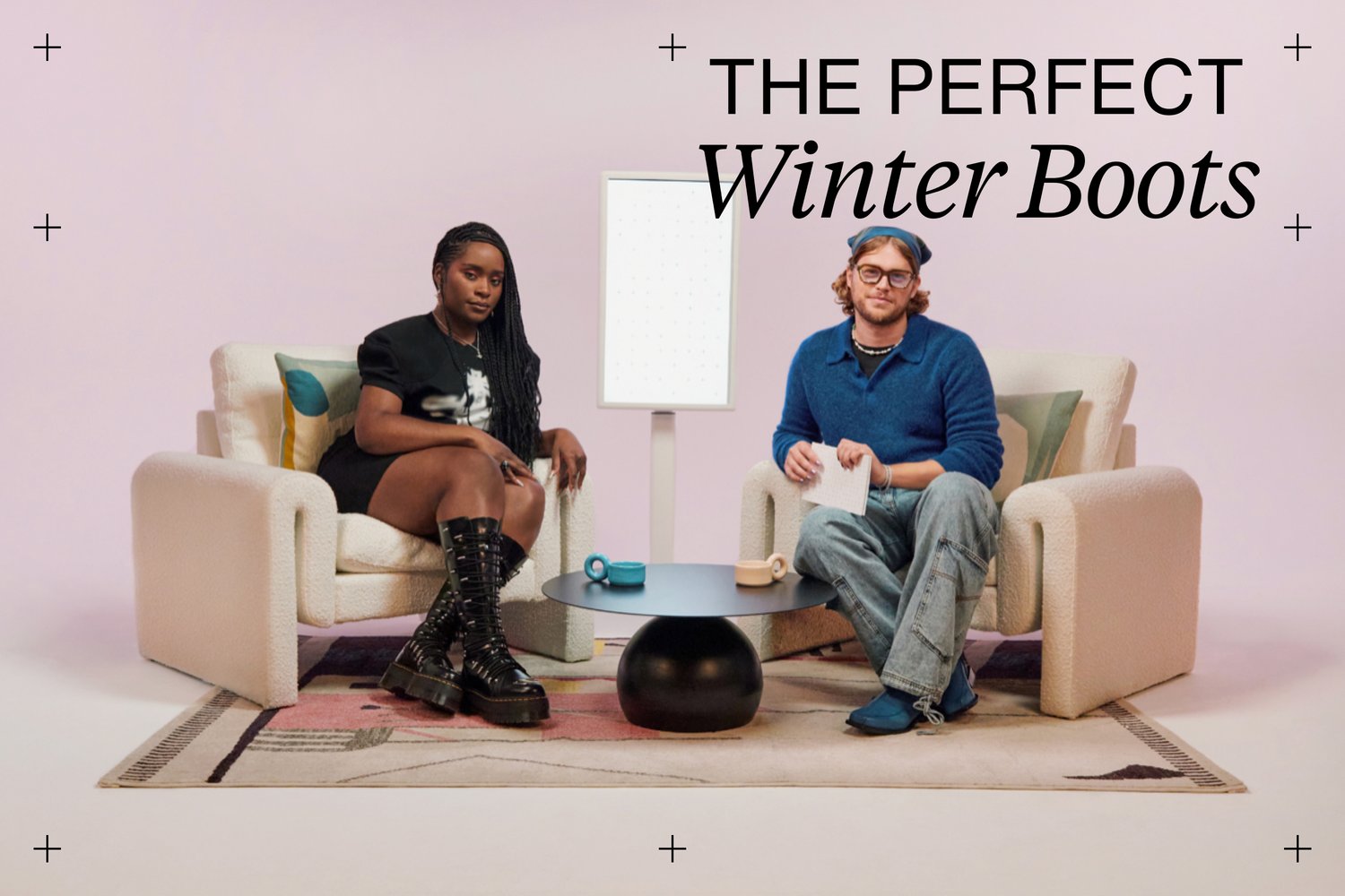 Two individuals sit on stylish chairs with a minimalist table, discussing winter boots against a soft pink backdrop.
