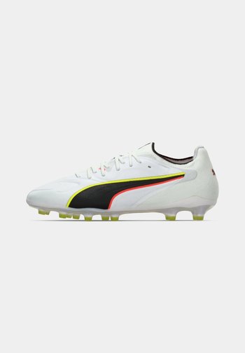 Hvitt fotballsko med svarte, gule og røde designdetaljer og gjennomsiktige gule knotter på sålen.