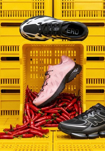 Chaussures de sport noir et blanc, rose et noir-gris exposées sur et autour de caisses jaunes remplies de piments rouges.