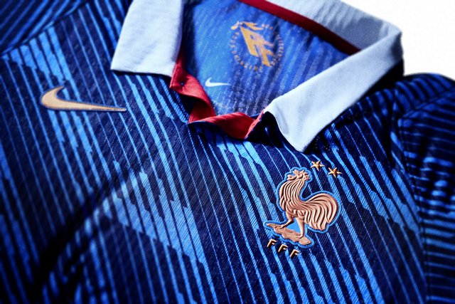 Koszulka piłkarska w niebiesko-granatowe paski z białym kołnierzem, złotym logo Nike oraz złotym godłem francuskiej federacji piłkarskiej z kogutem i trzema gwiazdkami.