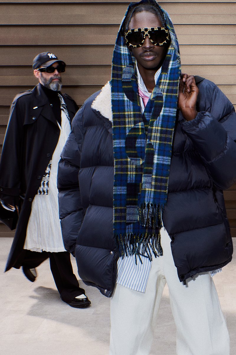 Four individuals showcase diverse fashion styles in an urban setting, featuring a mix of oversized outerwear, unique accessories, and casual attire.