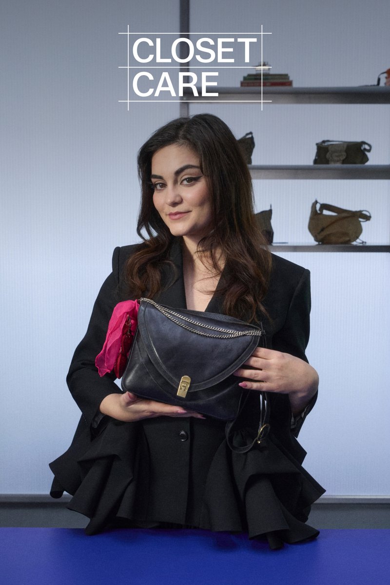 A woman in a black blazer holds a black handbag and a red accessory. Shelves behind her display various bags. Text above reads "CLOSET CARE."