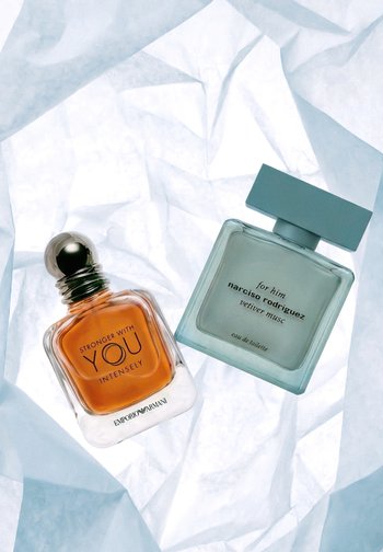 Zwei Parfümflaschen auf zerknittertem weißen Papier: Emporio Armani "Stronger With You Intensely" (bernsteinfarbene Flüssigkeit) und Narciso Rodriguez "for him vetiver musc."