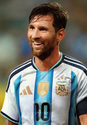 Joueur de football masculin avec barbe souriant, portant le maillot de l'Argentine avec le numéro 10, le badge des champions FIFA 2022 et le logo de l'AFA.
