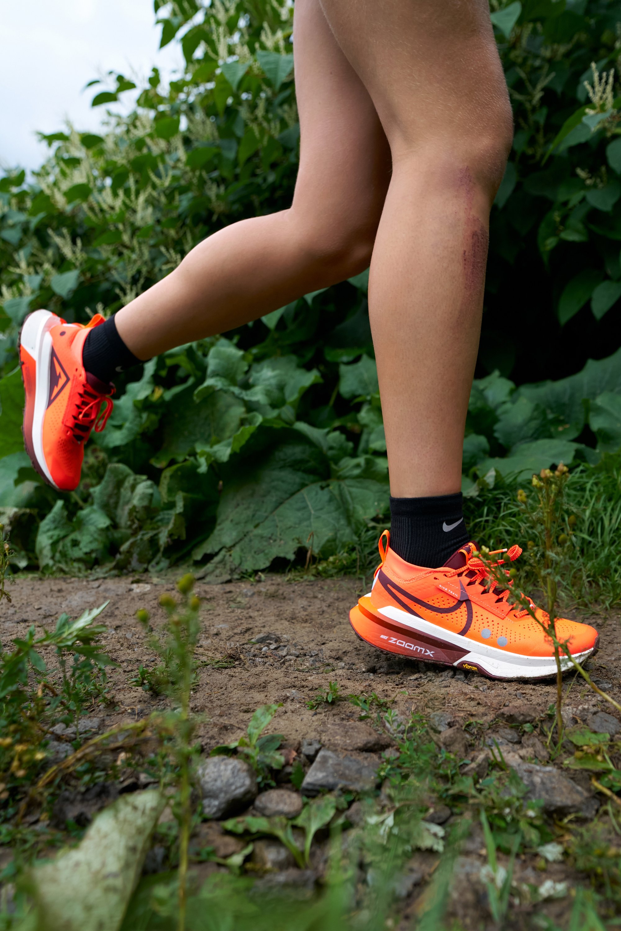 Bright orange athletic shoe with black accents and a textured upper. Features laces, a padded collar, and a prominent white and black sole.