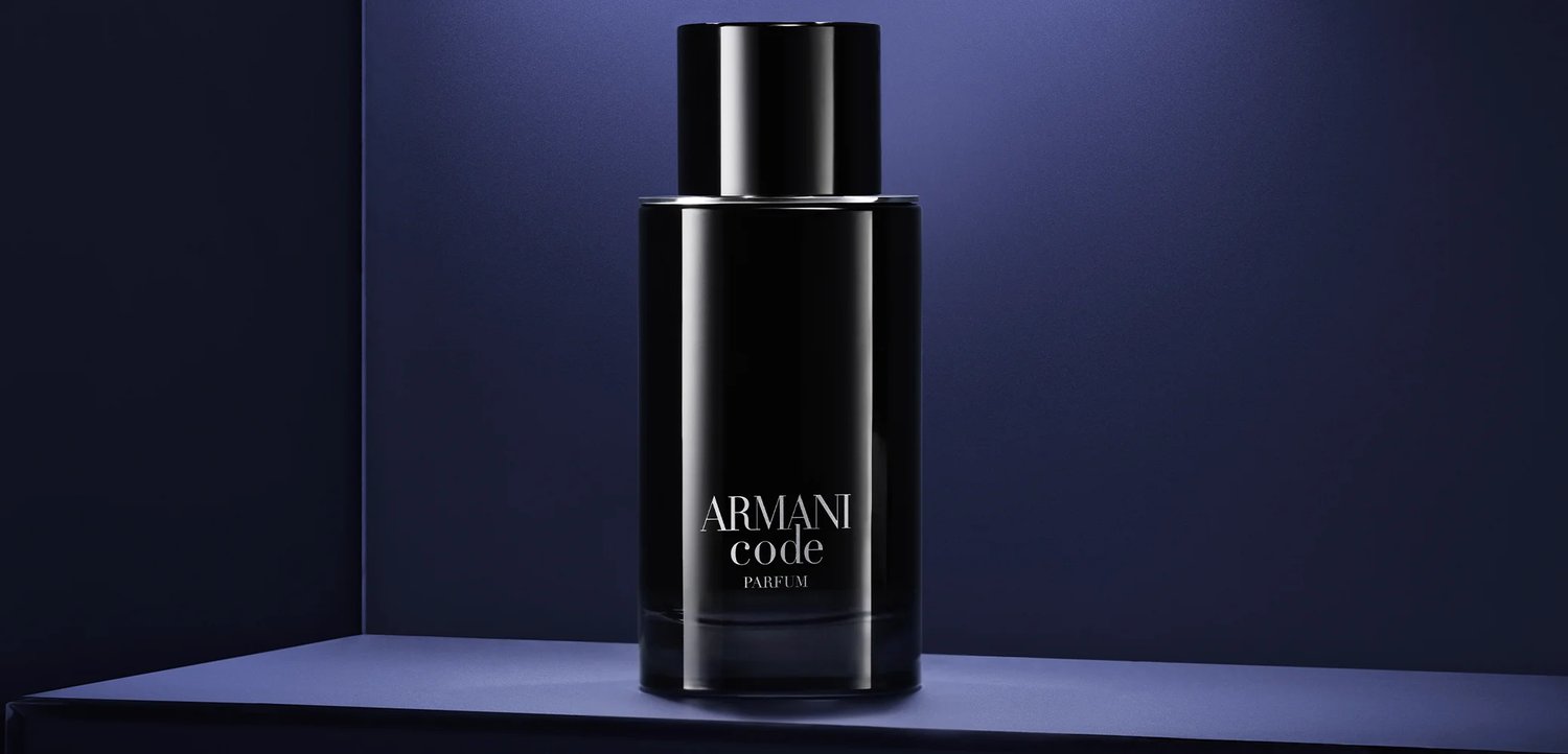 Black Armani Code Parfum bottle with white text, placed on a dark blue surface against a dark blue background.