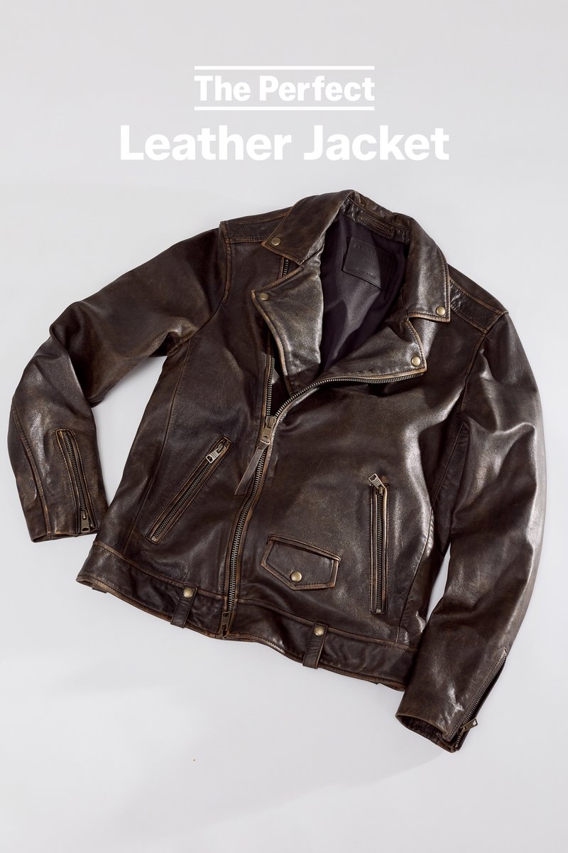 Dark brown leather biker jacket with zipper pockets, snap-button collar, and asymmetrical front zipper on a light gray background.