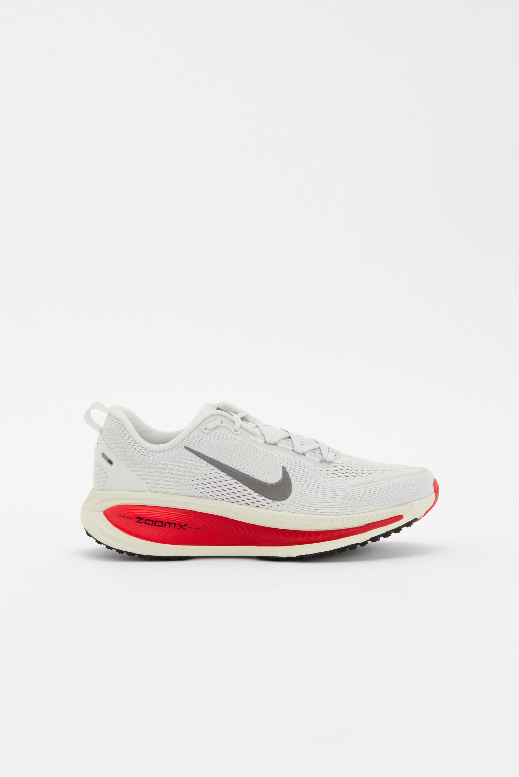 Una zapatilla de correr Nike blanca con un swoosh gris y una entresuela roja, en un ángulo que muestra el diseño y la suela.