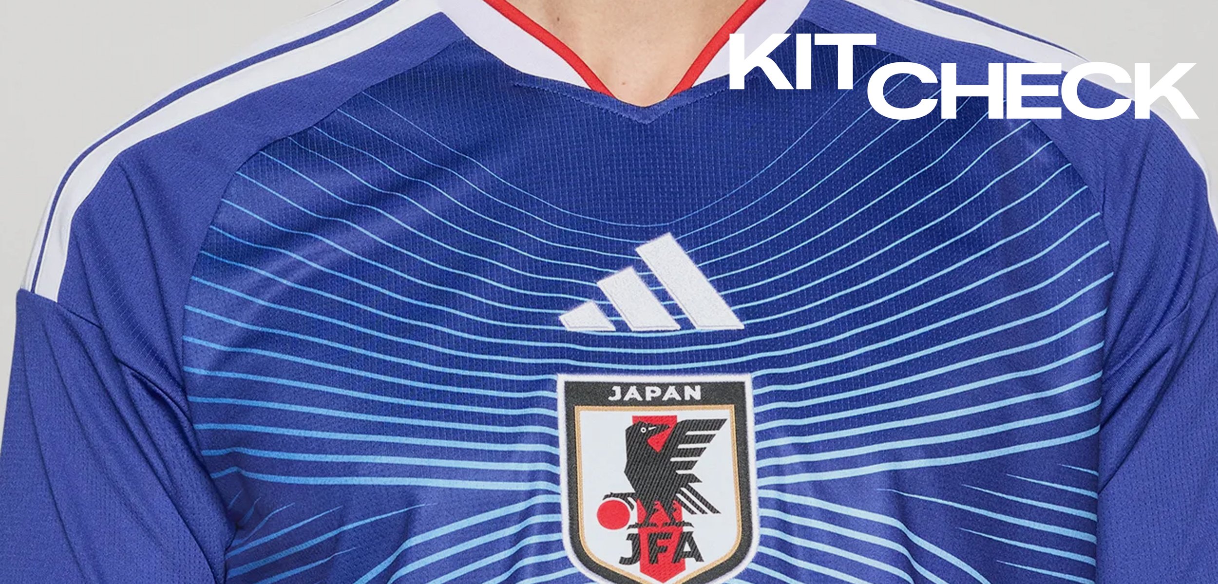 Blaues japanisches Fussballtrikot mit weißem Adidas-Logo, Emblem des Japan Football Association mit einem schwarzen Vogel und roter Sonne sowie weißen Streifen an den Ärmeln.