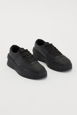 Zwarte sneakers van glad leer met een getextureerde rubberen zool, voorzien van ronde veters, geperforeerde accenten en een strakke vormgeving.