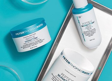Productos de cuidado de la piel a base de péptidos de Peter Thomas Roth en envases blancos y azules, que incluyen un tarro de crema, una botella de loción y un tubo de suero alisador.