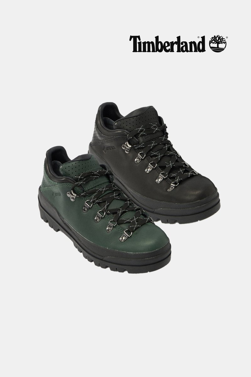 Ein Paar Timberland Wanderschuhe, ein dunkelgrünes und ein schwarzes, mit dicken Gummisohlen und Metallösen für Schnürsenkel.