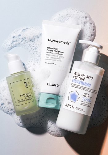 Trzy produkty do pielęgnacji skóry na bąbelkach pianki: serum Numbuzin, pianka do mycia Dr. Jart+ Renewing Foam Cleanser oraz balsam do ciała APLB z peptydami kwasu azelainowego.
