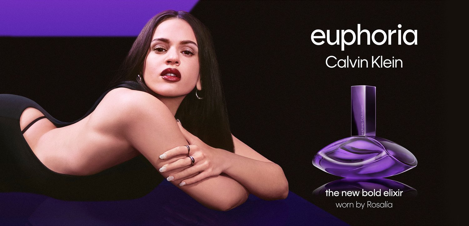 Kvinde med langt mørkt hår, der ligger på siden i sort tøj, ved siden af en lilla parfume flaske mærket "euphoria" af Calvin Klein.