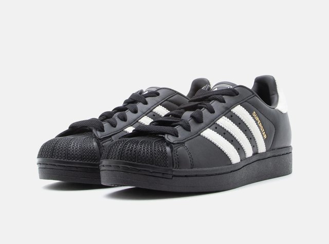 Paire de baskets noires Adidas Superstar avec des bandes blanches, des lacets noirs et un texte doré "Superstar" sur le côté.