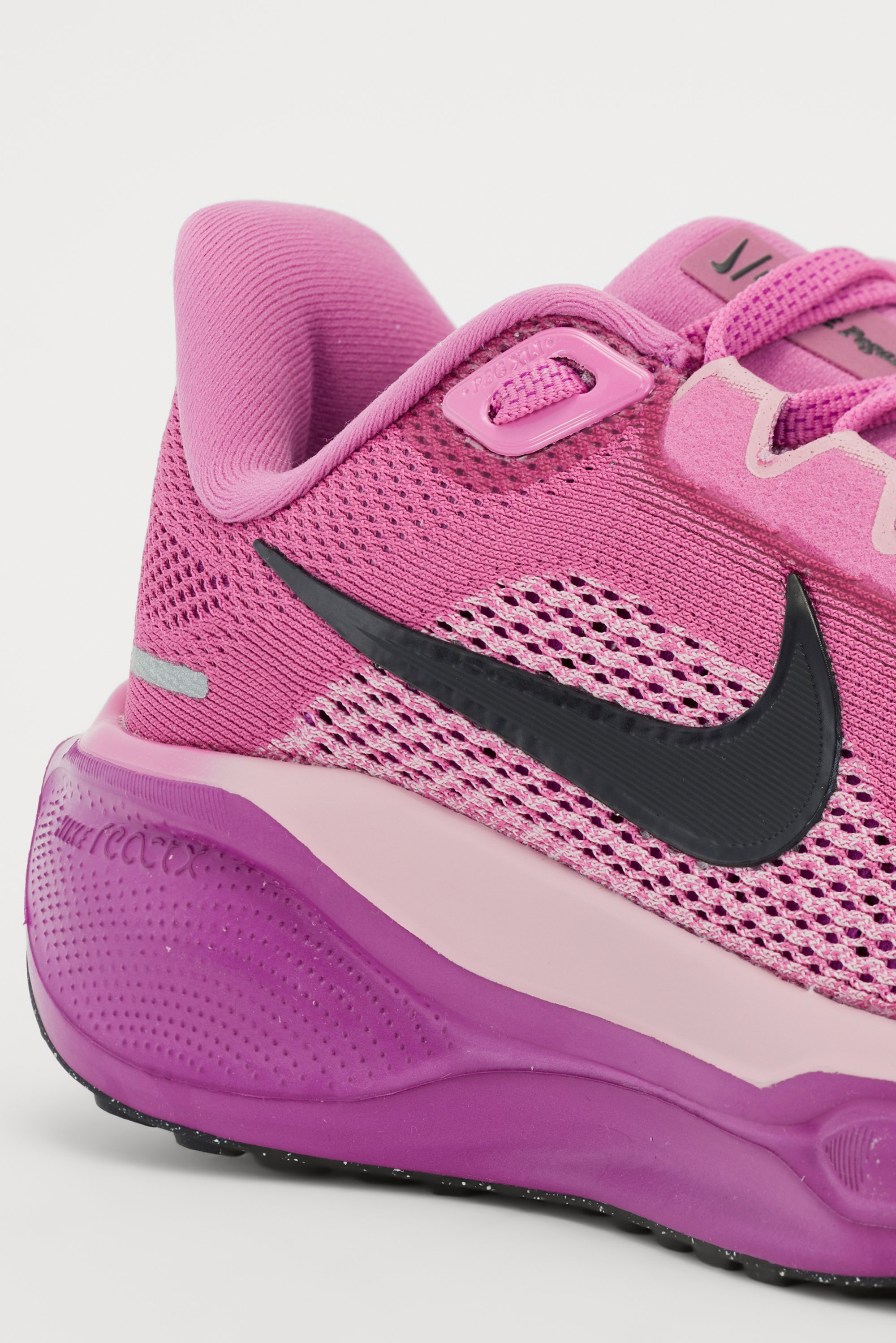 Zapatilla deportiva rosa con parte superior de malla, swoosh de Nike en negro, entresuela en rosa y púrpura, y suela exterior de goma texturizada para mayor tracción.