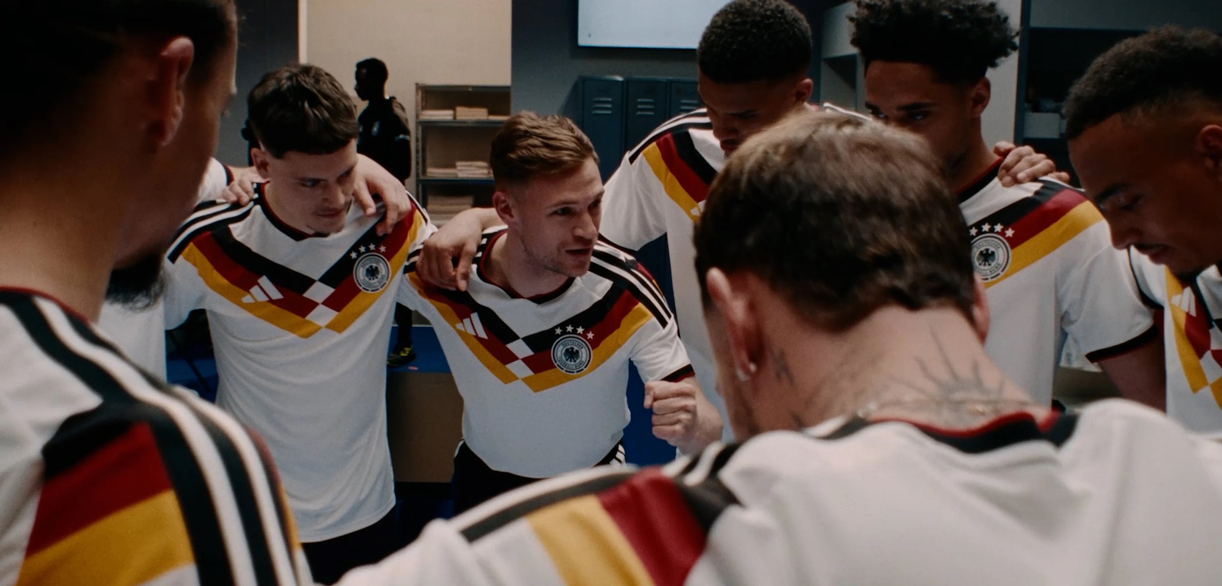 Fußballspieler in Deutschland-Trikots versammeln sich in der Umkleidekabine und zeigen vor einem Spiel Teamgeist und Konzentration.