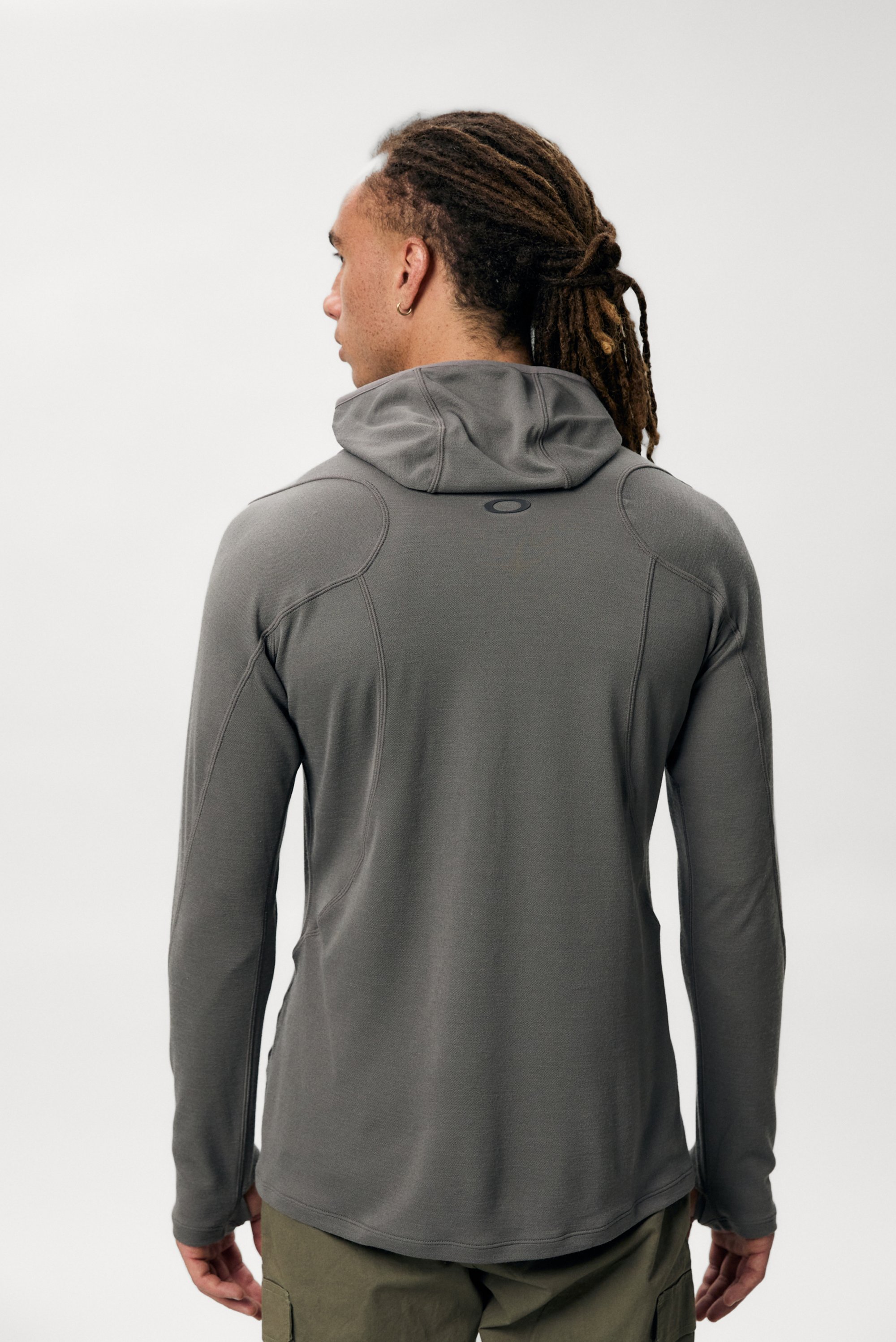 A person with dreadlocks wears a gray hoodie, facing away from the camera against a plain background, showcasing the garment's features.