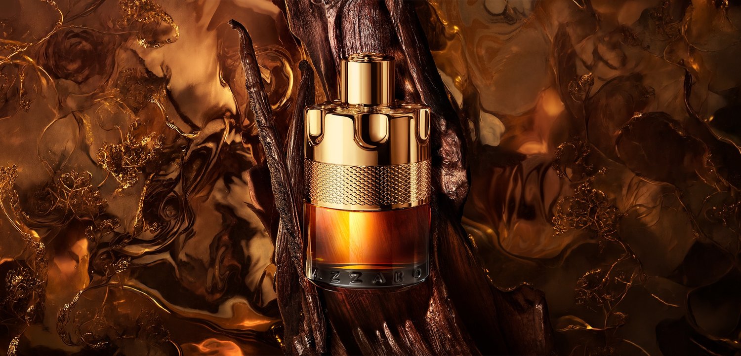 Gouden en amberkleurige parfumfles rustend op getextureerd donker hout met een warme, draaikolkachtige bruine en gouden abstracte achtergrond.