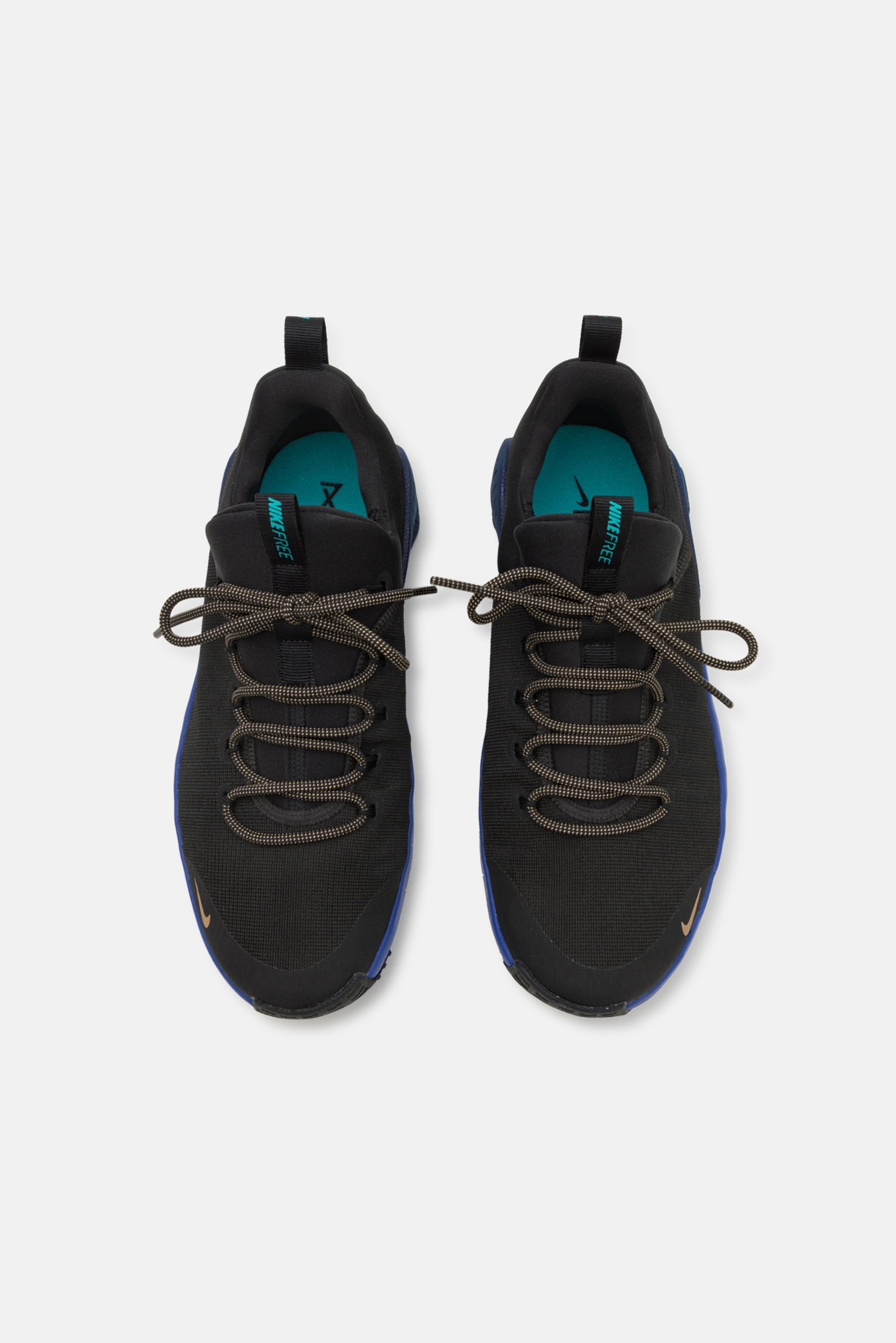 Zapatillas deportivas negras con acentos azules, con cordones marrones y una parte superior texturizada. Las plantillas son de color azul verdoso con el logotipo "NIKE FREE" visible.