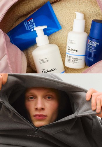 Collezione di prodotti per la cura personale che include bottiglie bianche e blu, un gel doccia blu e una felpa in pile grigia con collo con zip.