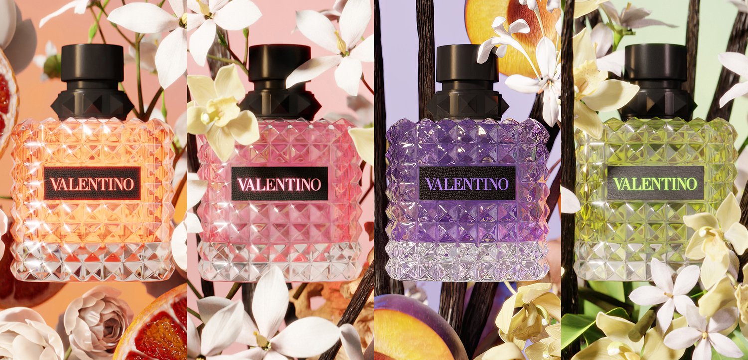 Vier Valentino parfumflesjes in oranje, roze, paars en groen, omringd door witte bloemen en fruitplakjes in een kleurrijke setting.
