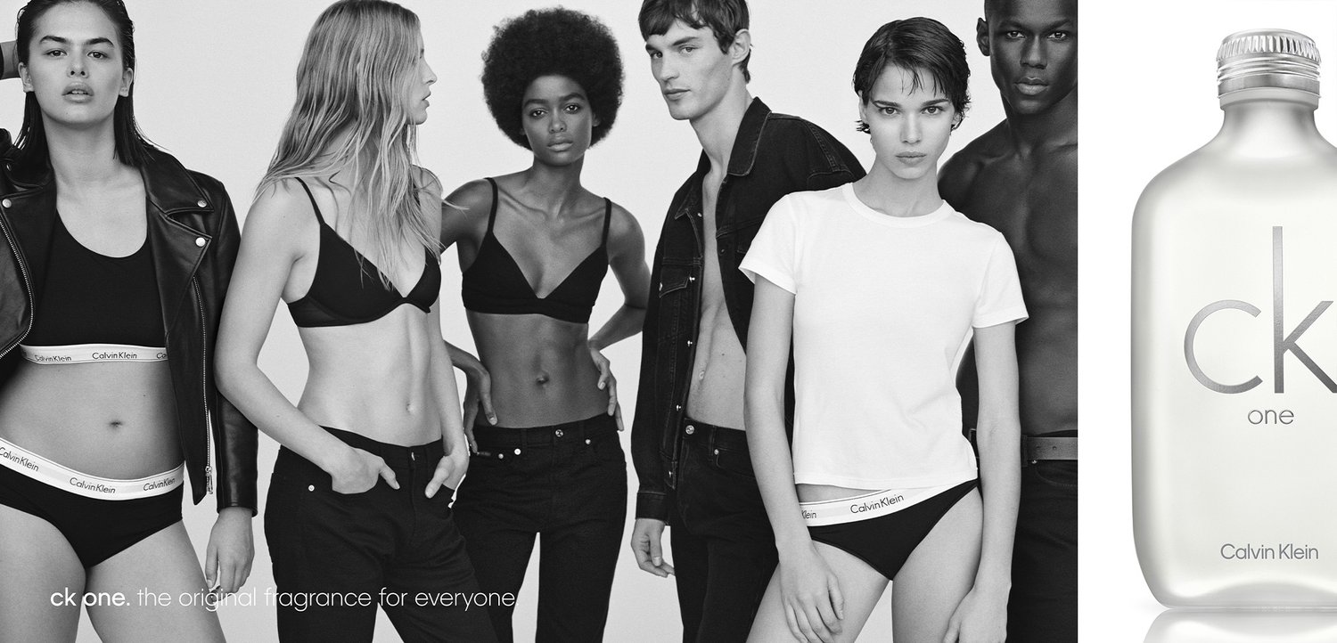 Cinque modelli diversi in biancheria intima e abbigliamento casual Calvin Klein in bianco e nero stanno accanto a una bottiglia del profumo CK One.
