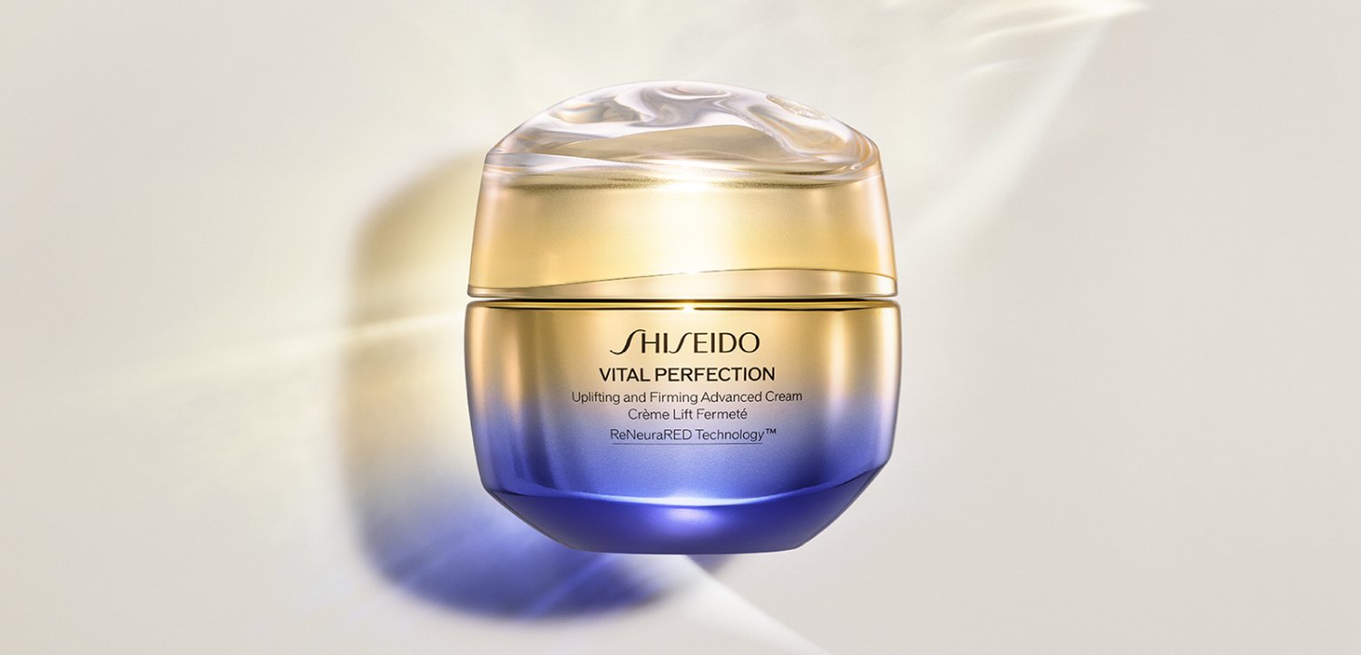 Pot de crème Shiseido Vital Perfection avec un dégradé or et violet, mettant en avant les propriétés raffermissantes et liftantes des soins de la peau.