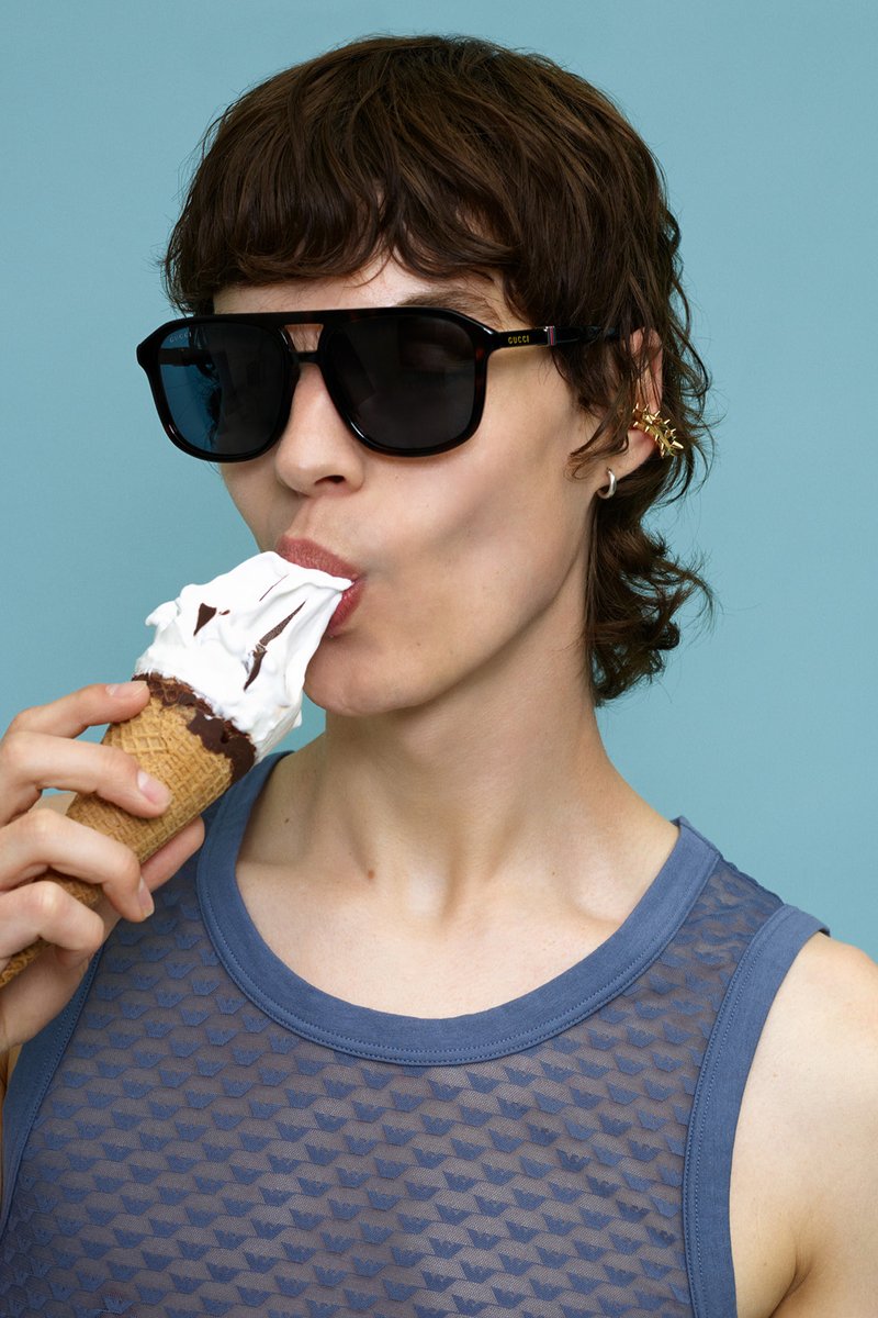 Ochelari de soare Gucci cu lentile întunecate, un top din bumbac texturat de culoare bleumarin și un cornet de înghețată cu frișcă și sos de ciocolată.
