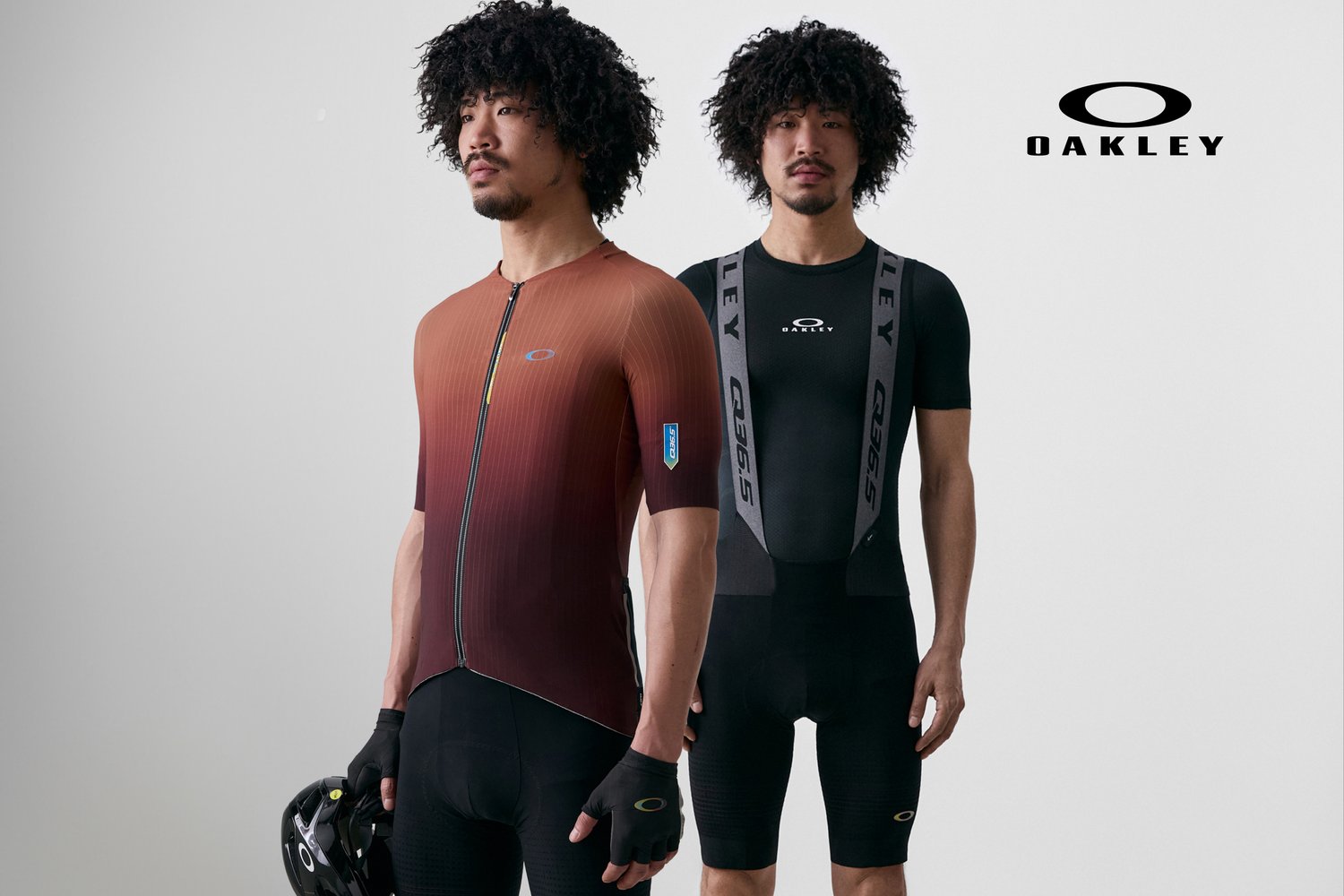 Dos hombres con cabello rizado llevan ropa de ciclismo: uno con una camiseta de gradiente naranja, el otro con un atuendo negro con tirantes. Se puede ver un logo de Oakley.