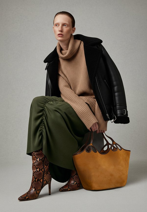 Knit tan jumper, green skirt with ruching, snake-print heeled boots, and a yellow suede tote bag with cut-out handles.