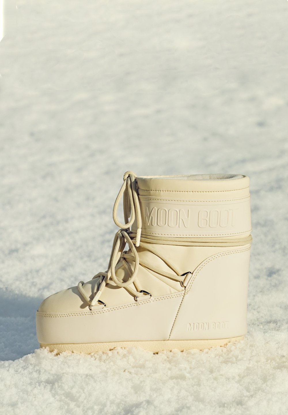 Bézs színű bélelt csizma sima bőr felülettel, kerek orral és dombornyomott "MOON BOOT" logóval. Fűzőkkel és vastag, texturált talppal rendelkezik.