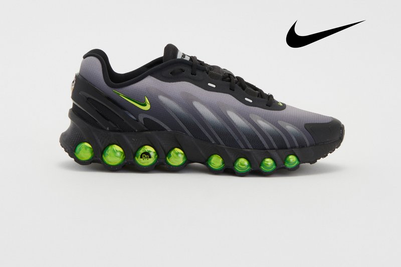 Graue und schwarze Nike-Sneaker mit einem einzigartigen Design und grünen Luftbläschen in der Sohle sowie einem auffälligen Nike-Logo.