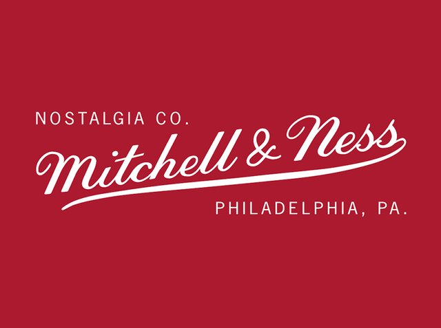 Czerwone tło z białym tekstem pisanym skryptem. "Nostalgia Co." na górze, poniżej "Mitchell & Ness" w większej, wygiętej czcionce. "Filadelfia, PA." poniżej.