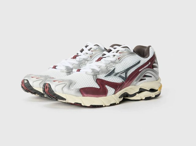 Λευκά αθλητικά παπούτσια από διχτυωτό υλικό με κόκκινες και ασημένιες λεπτομέρειες, μαύρη καουτσούκ σόλα και υφές στην επιφάνεια, με ορατό λογότυπο στο πλάι.