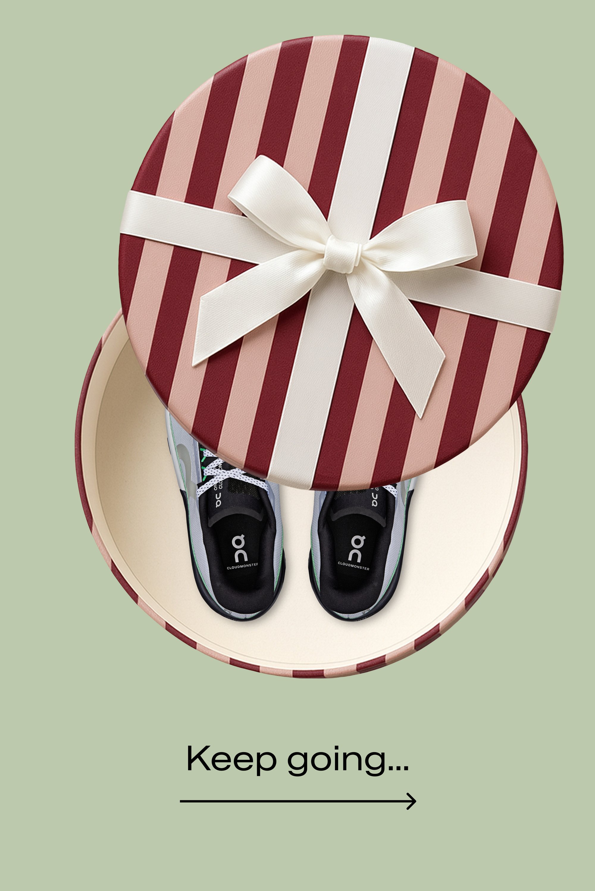 Caja de regalo redonda con rayas rojas y rosas, atada con un lazo blanco, que contiene zapatos deportivos negros con detalles verdes y texto de logo.