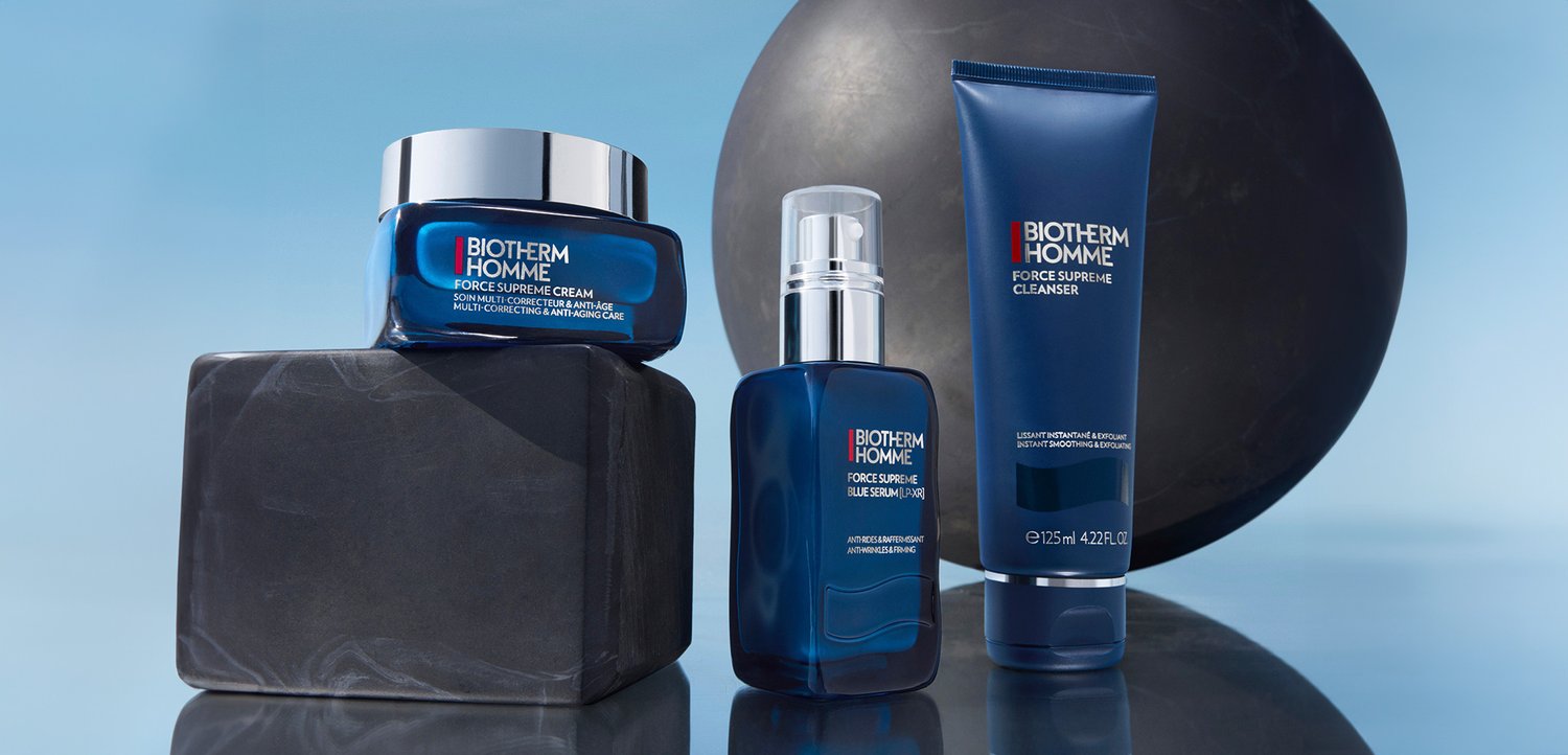 Drei Biotherm Homme Hautpflegeprodukte: eine Creme, ein Serum und ein Reiniger, präsentiert auf einem schwarzen Marmorblock mit einer dunklen Kugel im Hintergrund.