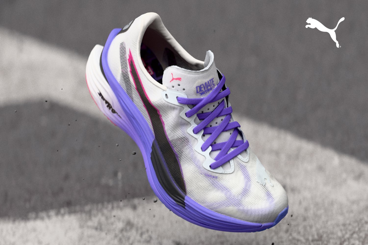 Zapatillas de running Puma con una parte superior blanca y acentos en púrpura y negro, un diseño texturizado y una suela púrpura. Los cordones coinciden con el color de la suela.